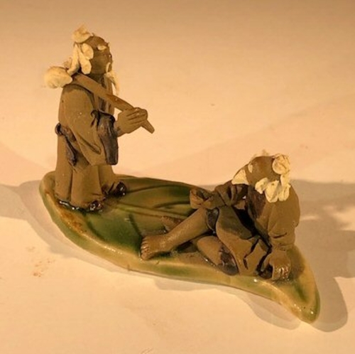 Miniature Ceramic Figurine Two Mud Men On A Leaf, One Standing Holding