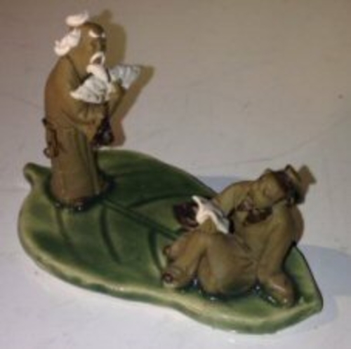 Miniature Ceramic Figurine Two Mud Men On A Leaf, One Standing Holding